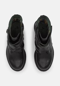 Botas de cuero negro hasta el tobillo con un diseño de puño doblado, cremalleras a los lados y una suela texturizada. El interior presenta un patrón de forro colorido.