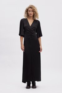 Black maxi dress with a deep V-neck, short bell sleeves, gathered waist detail, and a front slit. Smooth, shiny fabric with a draped silhouette.