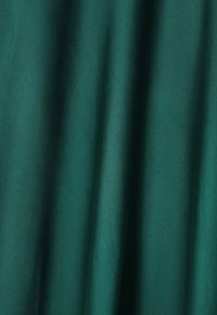 Tessuto verde scuro con una texture liscia, caratterizzato da morbidi drappeggi e una leggera brillantezza, adatto per varie applicazioni tessili.