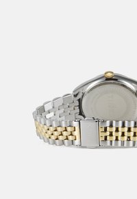Timex watch featuring a round silver case, gold crown, silver and gold metal link bracelet, and textured silver dial with branding on the back.
