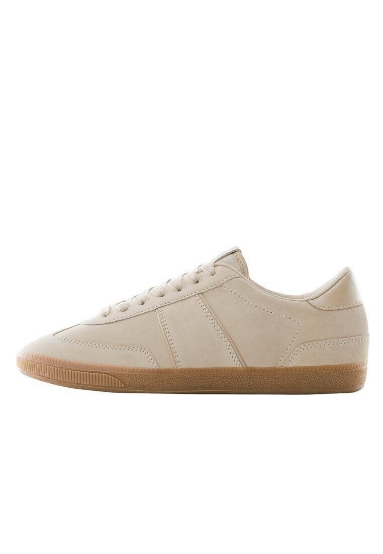 Beige tenisky s hladkým semišovým svrškem, gumovou špičkou a gumovou podrážkou. Vybavené plochými tkaničkami a jemnými švy.