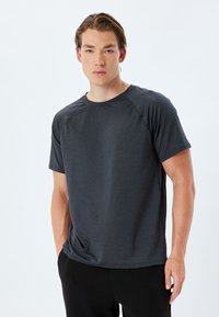 T-shirt atletico da uomo leggero di colore grigio scuro, con maniche corte, collo a giro e cuciture raglan; tessuto morbido e traspirante.
