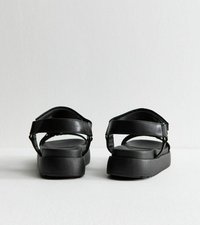 Svarta sandaler med platt sula, utrustade med två justerbara remmar över framdelen och en mjuk, texturerad yta. Minimalistisk design och diskreta detaljer.