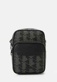 Melnas plecu soma ar ģeometrisku rakstu, viegli gluda āda priekšpusē, uz kuras ir redzams logo un rāvējslēdzēja aizdare, taisnstūra forma un regulējams siksniņa.