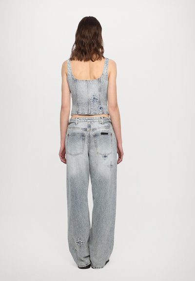 Denim co-ord set featuring a fitted crop top and wide-leg jeans, both in light wash with subtle distressed detailing and cross embellishments.