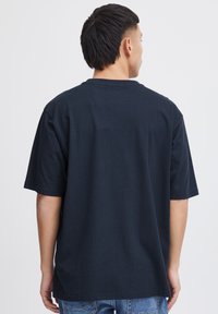Black cotton t-shirt with short sleeves and a round neckline, featuring a relaxed fit and smooth texture. Plain design, no additional details.