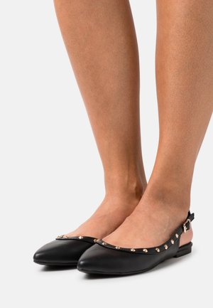 Zapatos planos slingback de cuero negro con punta puntiaguda, que cuentan con detalles de tachuelas doradas a lo largo del borde y un tacón bajo para mayor comodidad.