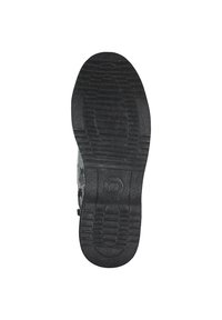 Czarna gumowa podeszwa buta z teksturowanym wzorem, zawierająca wyraźne rowki i okrągły akcent w centrum, zapewniający przyczepność i trwałość.