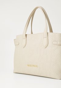 Cream leather tote bag with embossed Valentino logo pattern and gold-tone Valentino nameplate, featuring two handles.