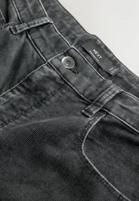 Tumedat hallid sirged teksapüksid tekstuurse viimistlusega, millel on metallist nööp sulgemiseks ja nähtavad õmblemise detailid.