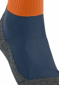 Un primo piano di una calza con una parte superiore arancione, un corpo blu e un fondo grigio, che mette in evidenza il suo design a strati e la texture del materiale.