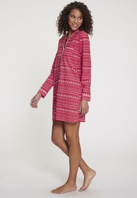 Crvena haljina s uzorkom koja ima duge rukave, ovratnik i patentni zatvarač, s geometrijskim dezenima u bijeloj i ružičastoj boji. Mekani materijal, dužine do koljena.