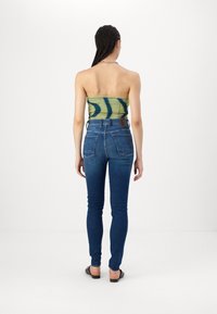 Green and blue strapless top paired with fitted blue jeans. The jeans have a classic design with back pockets and a mid-rise waist.