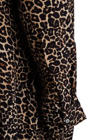 Leopardenmuster-Shirt in Schwarz und Beige, aus weichem Stoff, mit langen Ärmeln und Knopfdetails an den Bündchen.