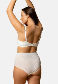 Soutien-gorge blanc avec bretelles réglables, associé à une culotte blanche taille haute ornée d'un motif géométrique texturé. Design lisse et sans couture.