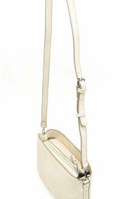 Prečna torba iz teksturiranega krem materiala z dolgo nastavljivo naramnico in zadrgo. Podrobnosti z obarvanjem v srebrni barvi.