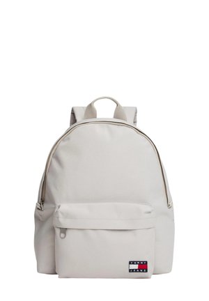 Zaino beige chiaro con tasca frontale con zip e manico superiore, caratterizzato da un piccolo logo Tommy Jeans sulla tasca frontale.