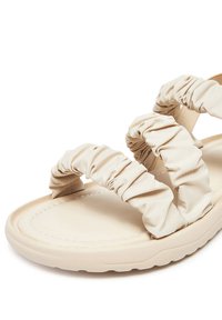 Beżowe sandały z trzema marszczonymi paskami z materiału, miękka gumowa podeszwa i gładka, wyprofilowana wkładka. Posiadają przeszywane krawędzie dla większej trwałości.