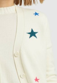 Cardigan crema realizzato in materiale morbido, caratterizzato da tre stelle ricamate in blu, verde acqua e rosa. Presenta una chiusura con bottoni e un colletto a coste.