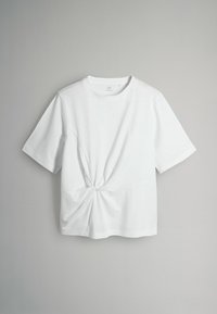 Balts īsām piedurknēm T-krekls, kas izgatavots no mīksta kokvilnas materiāla, ar mezglu detaļu jostasvietā un klasisku apaļu kakla izgriezumu.