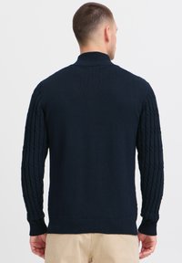 Suéter de punto azul marino con cuello alto, que presenta mangas de punto trenzado texturizado y bajo de canalé. Textura suave en el cuerpo, diseño casual.