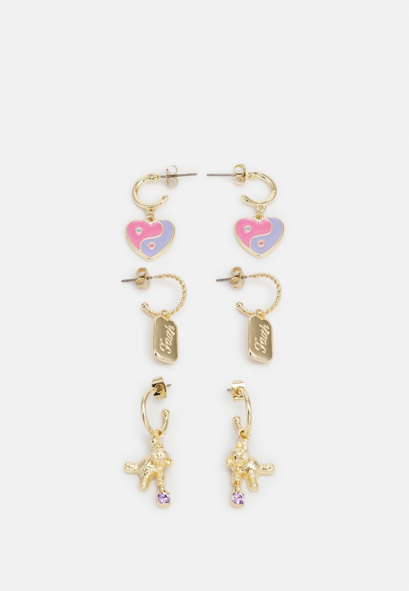 Brincos em tom de ouro com charms em forma de coração nas cores rosa e roxo, etiquetas gravadas e pendentes de ursinho de pelúcia com detalhes roxos.