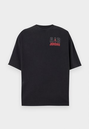 T-shirt noir à manches courtes avec "AIR" en blanc, logo Jumpman rouge et texte "JORDAN" en rouge sur la partie supérieure gauche de la poitrine.