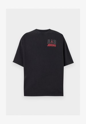Μαύρο κοντομάνικο T-shirt με την ένδειξη «AIR» σε λευκό, κόκκινο λογότυπο Jumpman και κόκκινο κείμενο «JORDAN» στο πάνω αριστερό μέρος του στήθους.