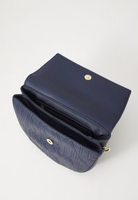 Sac à main en cuir bleu marine avec un motif texturé, quincaillerie dorée et fermeture à pression magnétique. À l'intérieur, il dispose de plusieurs compartiments et d'une doublure lisse.