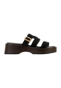 Sandale à plateforme noire avec trois brides et une boucle dorée sur la bride centrale réglable, dotée d'une semelle épaisse marron texturée.