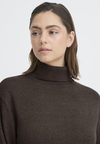 Barna garbó pulóver, puha anyagból, laza szabással, bordázott részletekkel a nyak és a mandzsetták körül.