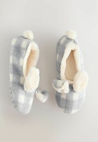 Hallidehallide, valged karvased sussid, mis on valmistatud pehmest fliisist, millel on kohev kreemjas aksent ja ümmargune kuju, mille peal on pom-pomid.