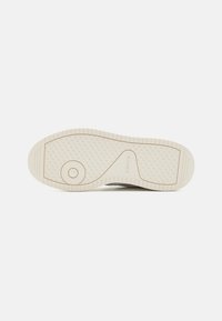 Levi's sneakersåle i kremfarge med et strukturert grep mønster. Har en sirkulær aksent og fremtredende merkevare langs siden.