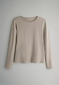 Bluza cu mâneci lungi și guler rotund, realizată dintr-un material moale bej, cu textură netedă și design simplu, fără modele sau ornamente vizibile.