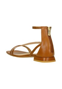 Sandal in pelle marrone con tacco piatto, punta aperta, cinturini incrociati e chiusura con zip sul retro per una facile calzata.