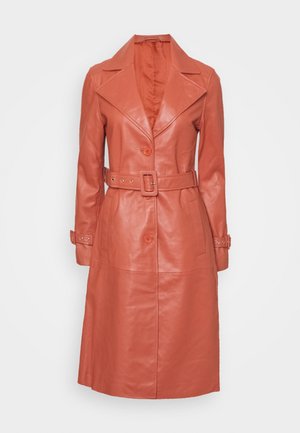 Long trench-coat en cuir couleur rouille avec de larges revers, taille ceinturée, fermeture par boutons et brides aux poignets des longues manches.