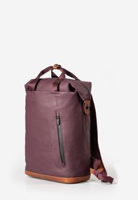 Zaino in pelle bordeaux con design a roll-top, tasca laterale con zip e fondo in pelle marrone. Dotato di spallacci imbottiti e un logo discreto.