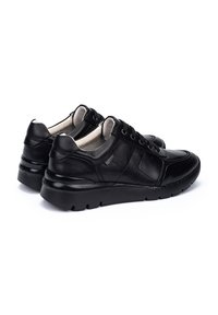 Zapatillas de piel negra con un acabado suave, punta redondeada, diseño de cordones, cuello acolchado y suela de goma texturizada para mayor agarre.