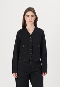 Veste en denim noir avec un col en V, fermeture à boutons, deux poches avant et manches longues. Elle présente un design structuré et court.