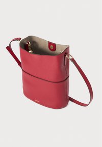 Sac seau en cuir rouge avec une texture lisse, doté d'une fermeture dorée, d'une courte bandoulière et d'une doublure intérieure beige contrastante.