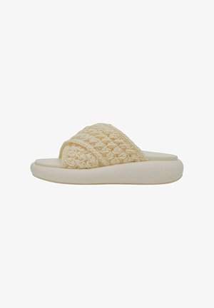 Sandales à glissière tissées beige avec une semelle arrondie rembourrée et un design croisé. La texture est douce avec une apparence subtilement patternée.