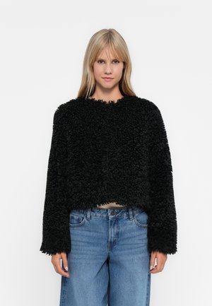 Black, fuzzy cropped sweater with a round neckline and long sleeves, paired with high-waisted blue jeans. Soft texture is prominent.