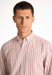 Camicia con colletto a righe verticali rosa e bianche, realizzata in tessuto testurizzato, con bottoni sulla parte anteriore e una vestibilità rilassata.