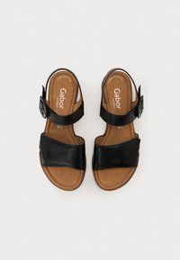Black leather sandals with a wide front strap, adjustable ankle strap, and a cushioned brown insole. Simple design, suitable for casual wear.