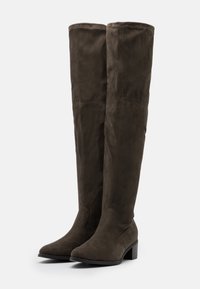 Botas marrones de ante hasta la rodilla con punta puntiaguda y tacón grueso. Textura suave con costuras cosidas y diseño ajustado.