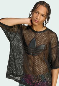 Black mesh oversized t-shirt with short sleeves, featuring a black leather Adidas logo on the chest and a colorful patterned undershirt.