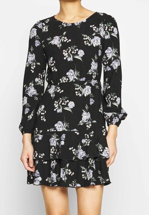 Musta pitkähihaisen minimekko, jossa vaaleanvioletti ja valkoinen kukkakuosi, röyhelöinen helma ja hieman puffitetut hihat.