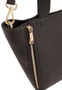 Zwarte leren handtas met een gestructureerde vorm, opvallende gouden ritsdetails en een afneembare schouderriem. Getextureerde afwerking versterkt de stijl.