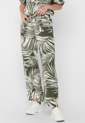 Pantalons larges verts ornés d'un motif de feuilles tropicales blanches et d'une taille nouée. Associés à un haut décontracté et des baskets blanches.