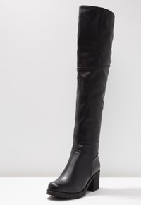 Bota negra de cuero hasta la rodilla con tacón grueso y textura lisa. Presenta punta redondeada y diseño minimalista.